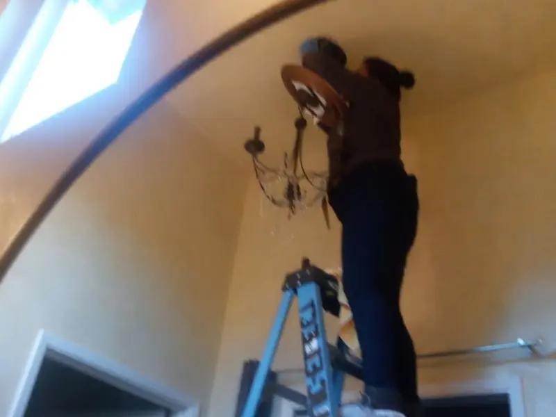 Electrician installing a chandelier in a Whitman residence